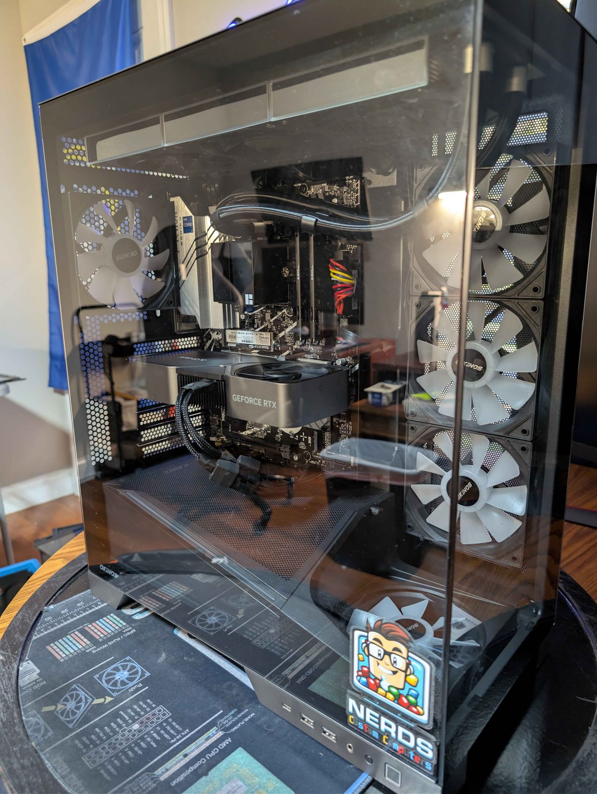 Custom PC build with rainbow RGB fans next to a lit-up gaming controller sign